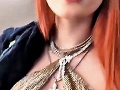 Bella Thorne with red hair and showing cleavage in a dress